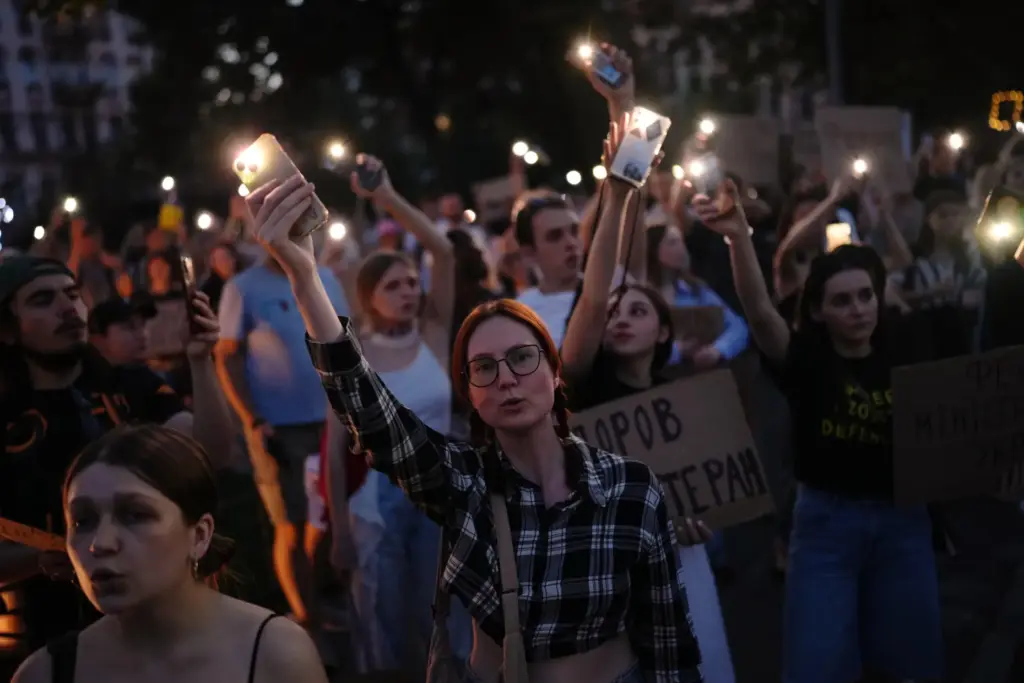 People sing and hold up their cellphone flashlights during a rally.
