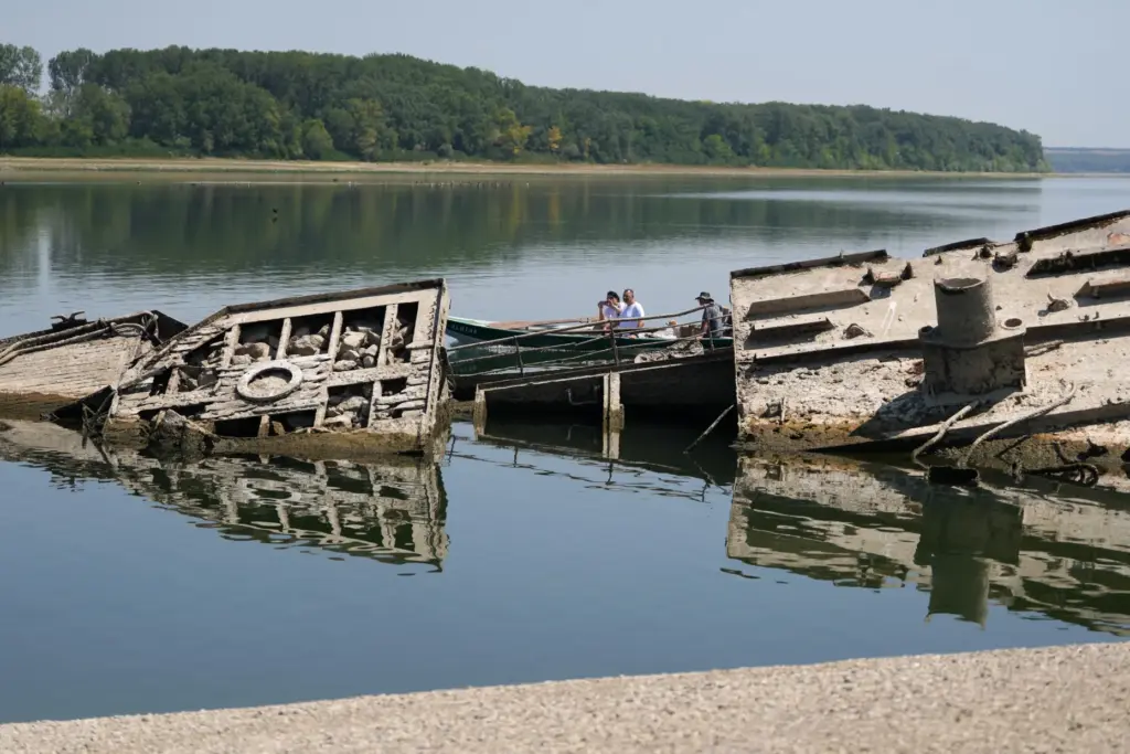 People watch the wreckage of a WWII German warship, emerged...