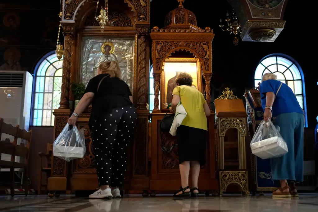 Pilgrims holding Fanouropites, orange-flavored cakes, kiss icons at the Church of St. Fanourios.