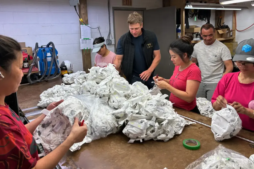 Wuxly CEO James Yurichuk and garment factory owner Aaron Ly inspect military helmet covers.