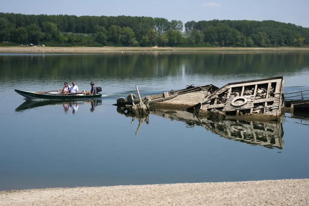 People watch the wreckage of a WWII German warship, emerged...