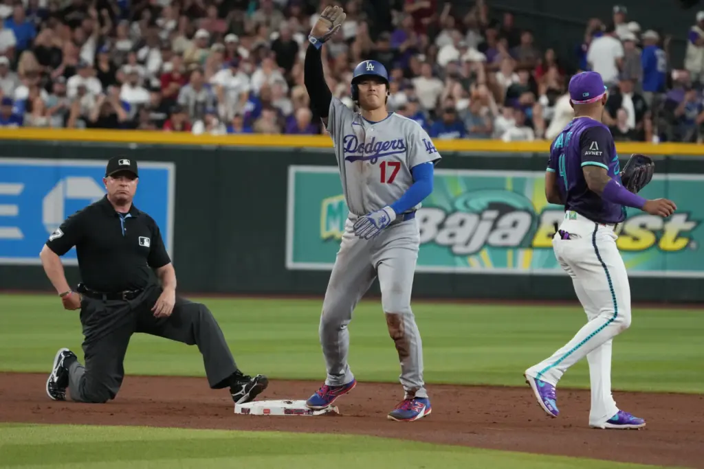 Dodgers star Shohei Ohtani, center, gestures to his dugout to...