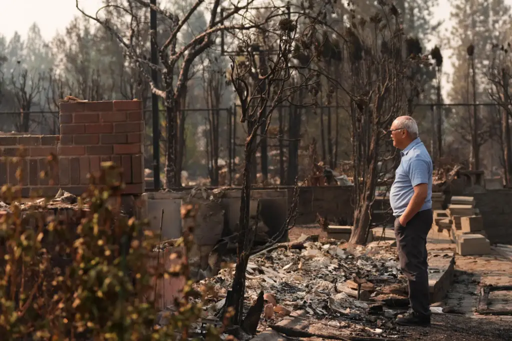 Daniel Sim, 76, views the remains of his destroyed house after a wildfire hit.
