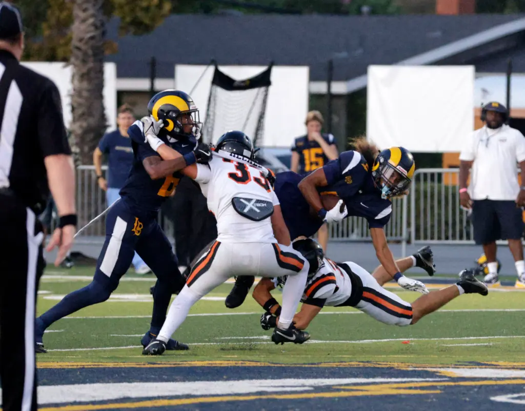 Millikans Aden Taufa (4) is tripped up by Huntington Beachs...