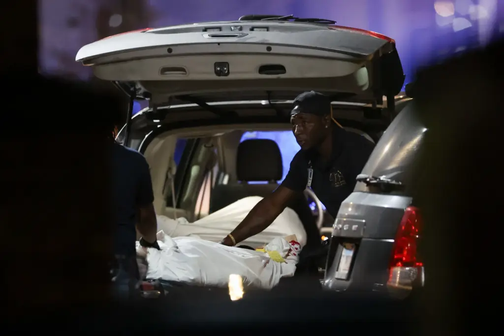 Workers transport a body early Aug. 7, 2026, from the...