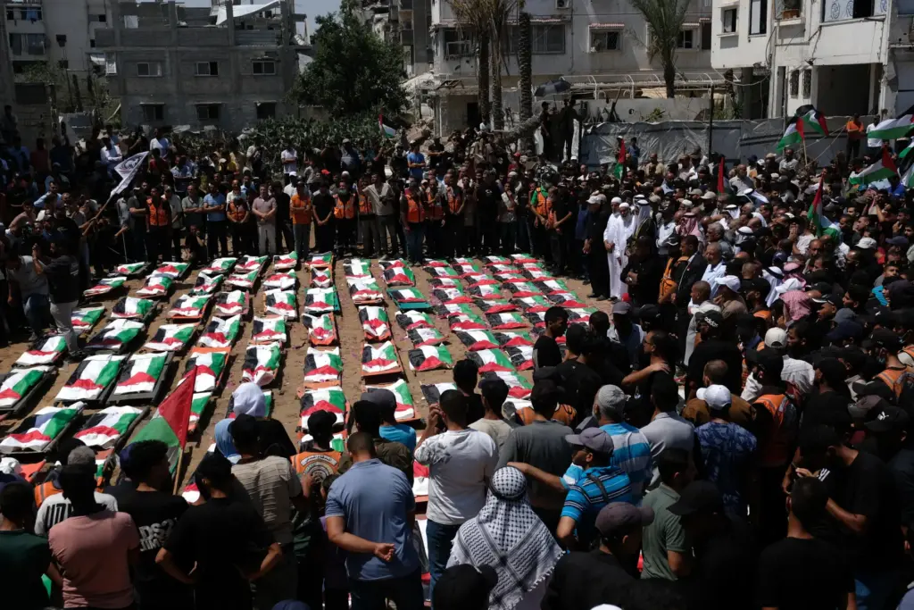 Mourners gather around the flag-draped bodies of members of the...