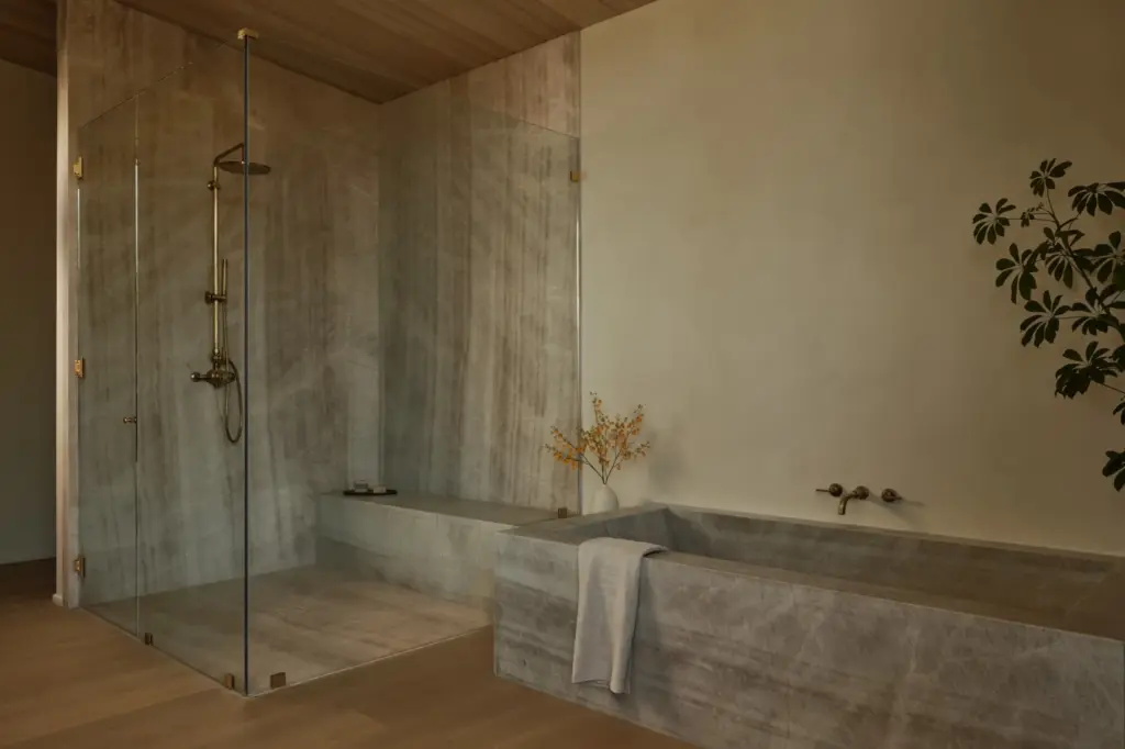The primary bathroom finished in Taj Mahal quartzite with Studio...