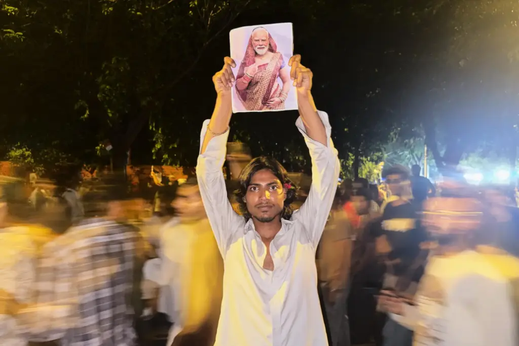 A protester holds a placard with a portrait of Indian Prime Minister Narendra Modi draped in a saree.