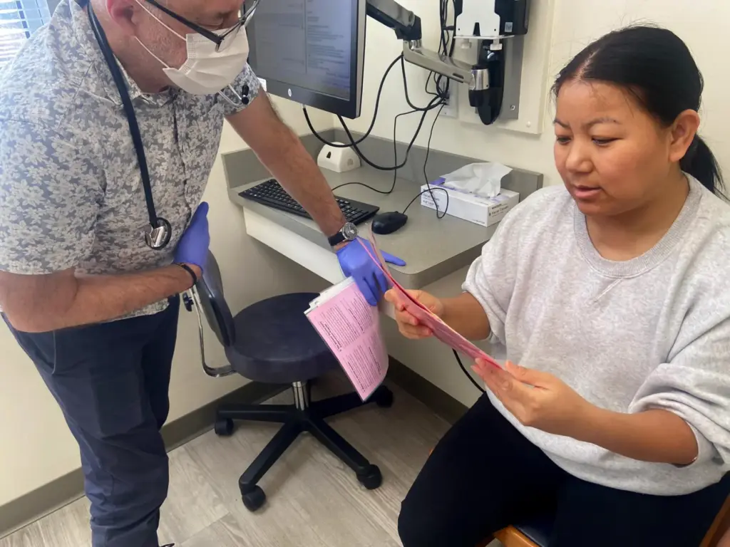 Pediatrician John Snyder gives vaccine information to Tenzin Dekey, who...