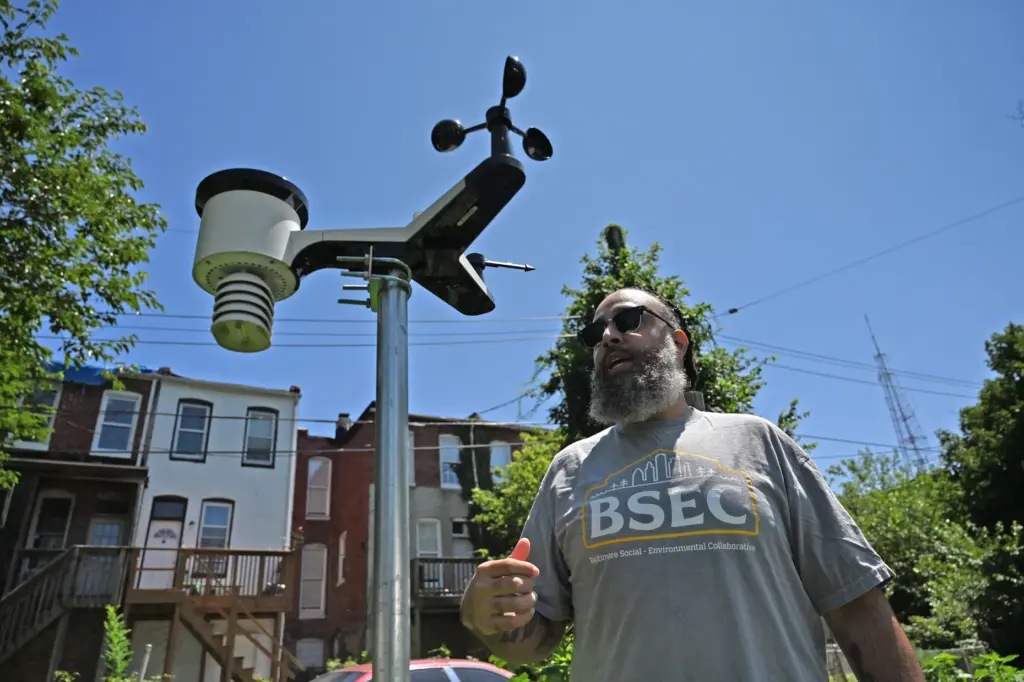 DJ Carter stands near the weather station at the Plantation Park Heights Urban Farm.