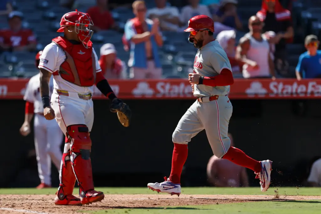 Philadelphia Phillies designated hitter Kyle Schwarber, right, runs home after...
