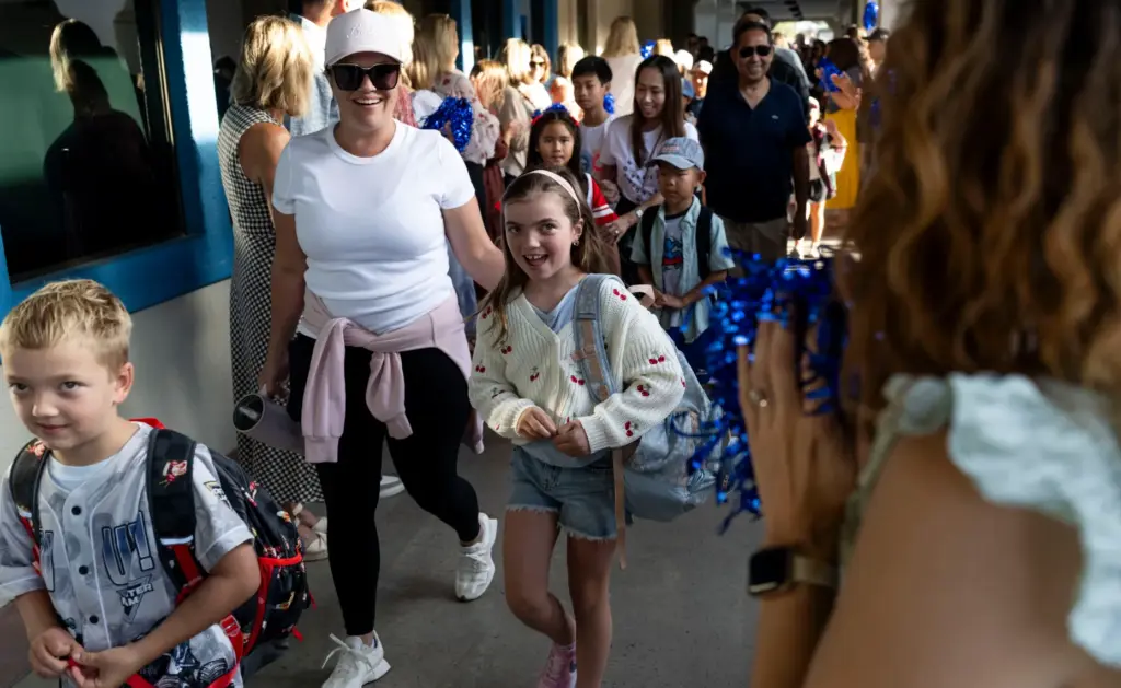 Charlotte Hartranft walks through a tunnel of cheering teachers with...