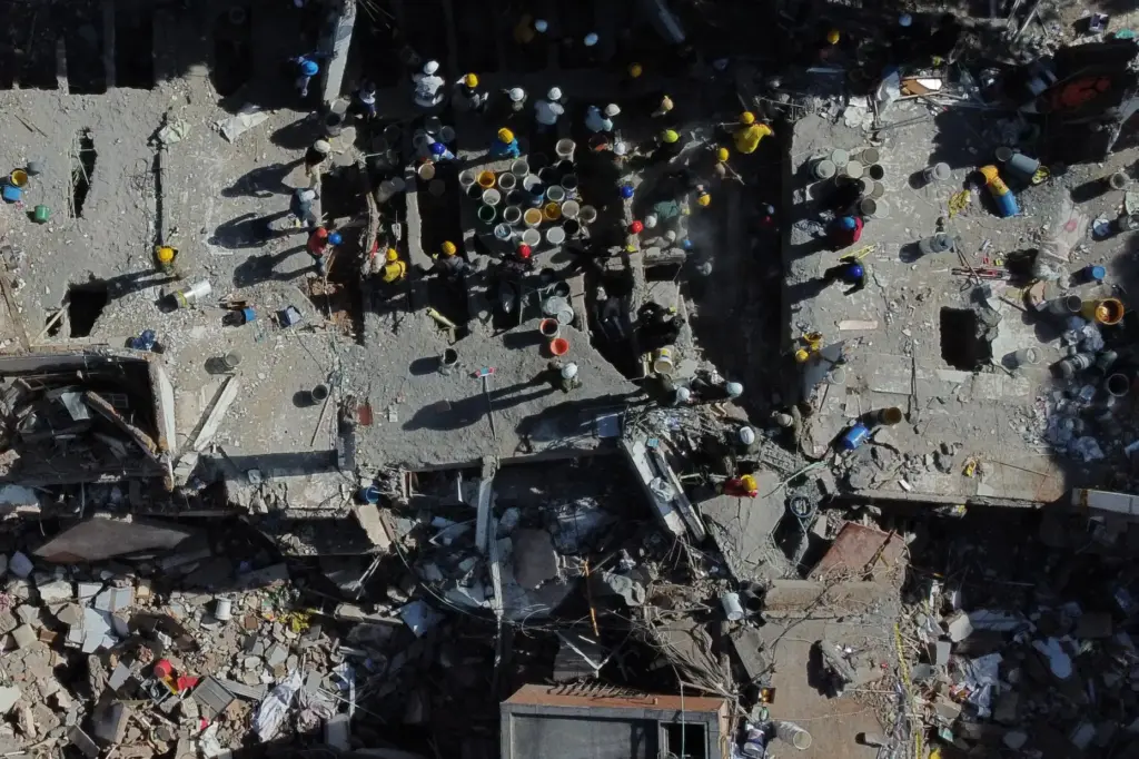 Volunteers and rescue workers use buckets to remove debris of a collapsed building.