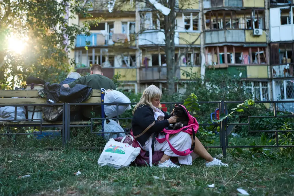 Local residents sit in front of heavily damaged residential buildings after an overnight Russian attack.