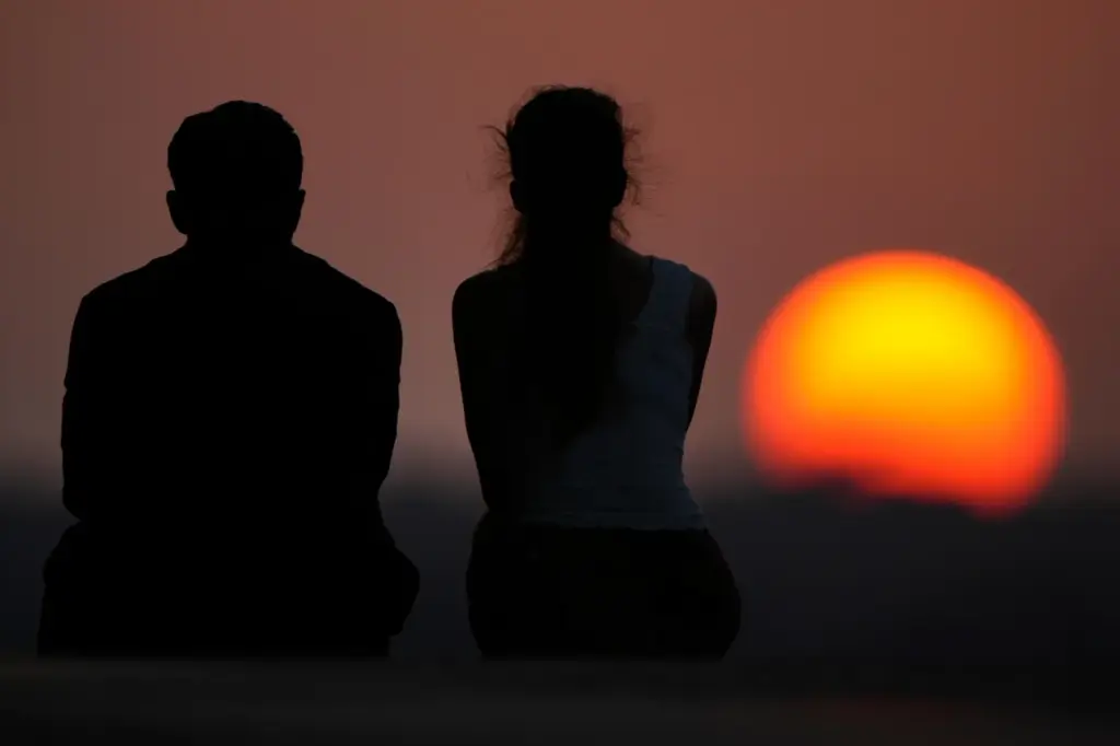 People watch the setting sun at the end of a hot day in Kansas City, Missouri.