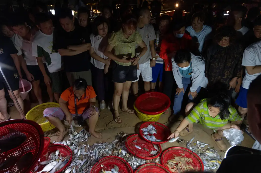 FILE – Locals and tourists gather to look at a...