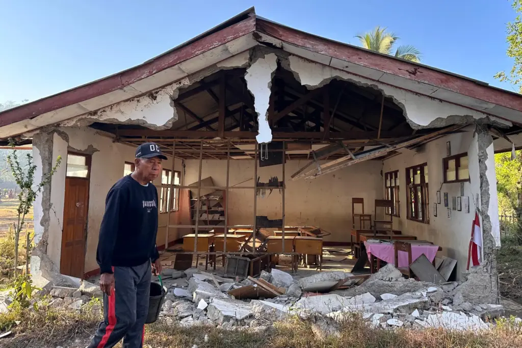 A man walks past an earthquake-damaged school in Satar Punda, Indonesia.