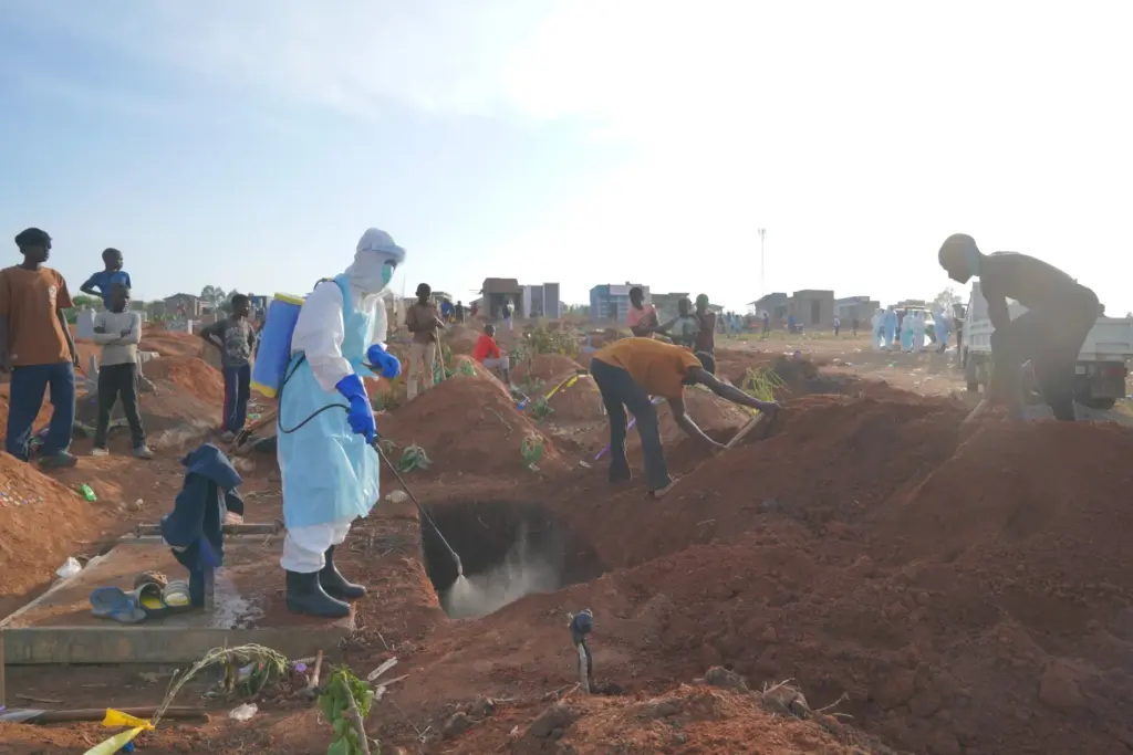 A health worker sprays disinfectant in a freshly dug grave.