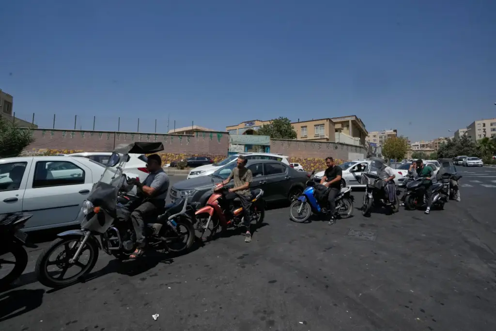 Motorcycles and cars line up outside a gas station in...