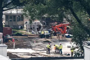Crews remove the granite seal on the White House helipad, signaling potential project delays
