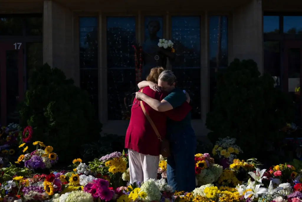 FILE – Women embrace at the memorial outside the Annunciation...