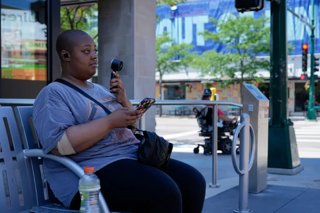 FILE – Simone Mosley waits for their ride in shade...