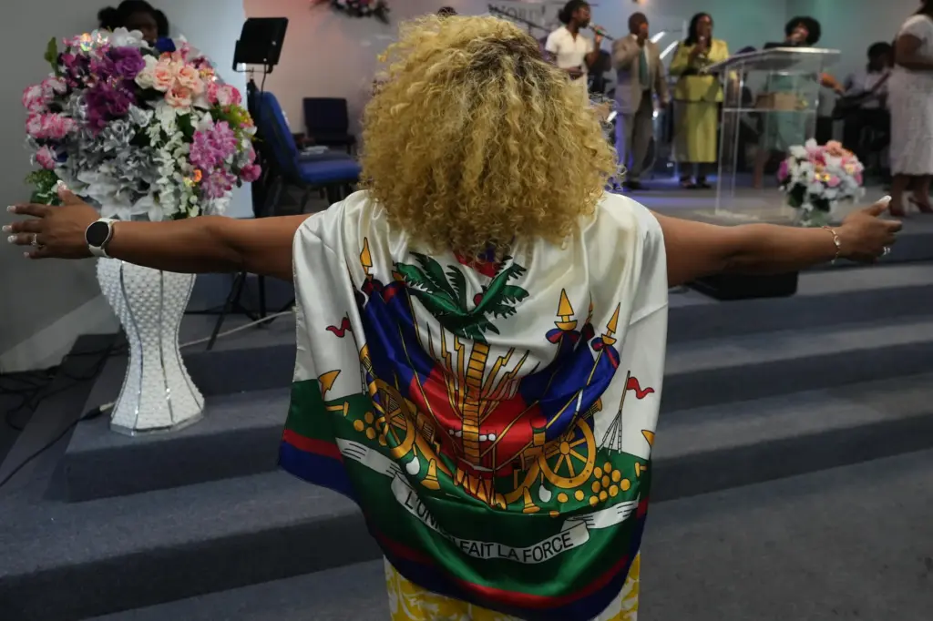 Marjorie EstimÃ© prays wearing a Haitian flag during a service at the Word of Life Center.