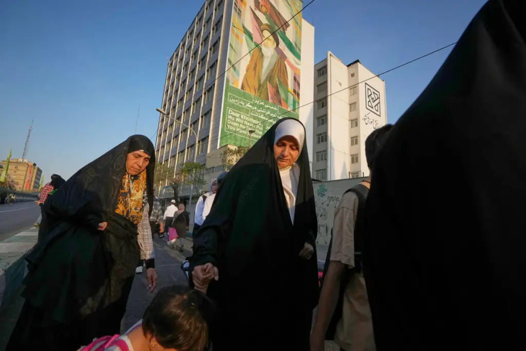 Women walk past a billboard depicting the late Iranian revolutionary...
