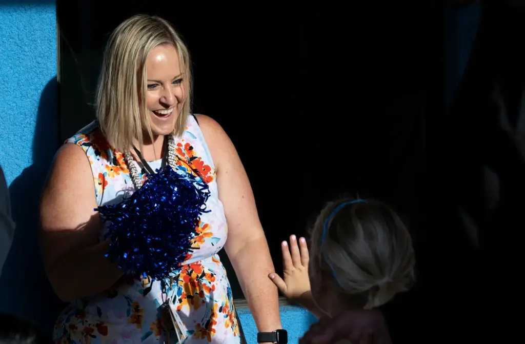 Teacher Katie Botsford greets a student walking through a cheering...