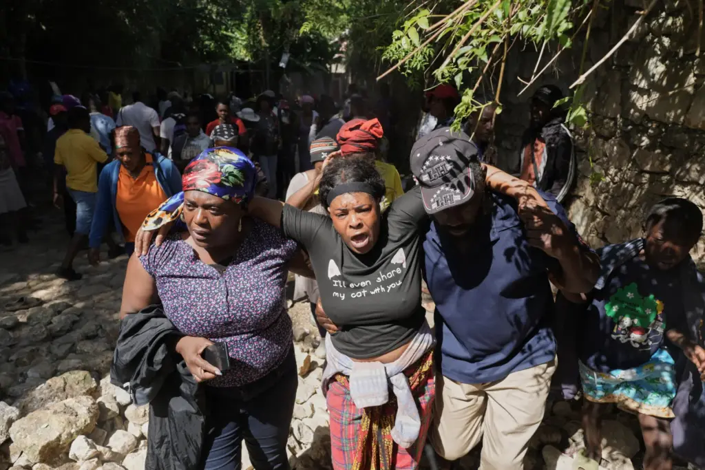 People watch as the bodies of their relatives who were...
