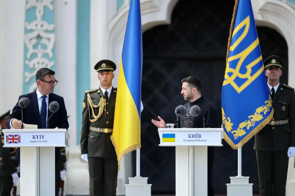 Britain's Prime Minister Andy Burnham looks at Ukraine's President Volodymyr Zelensky delivering a speech.