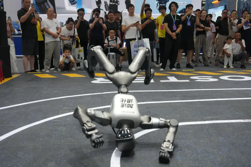 Visitors watch a humanoid robot at a booth.
