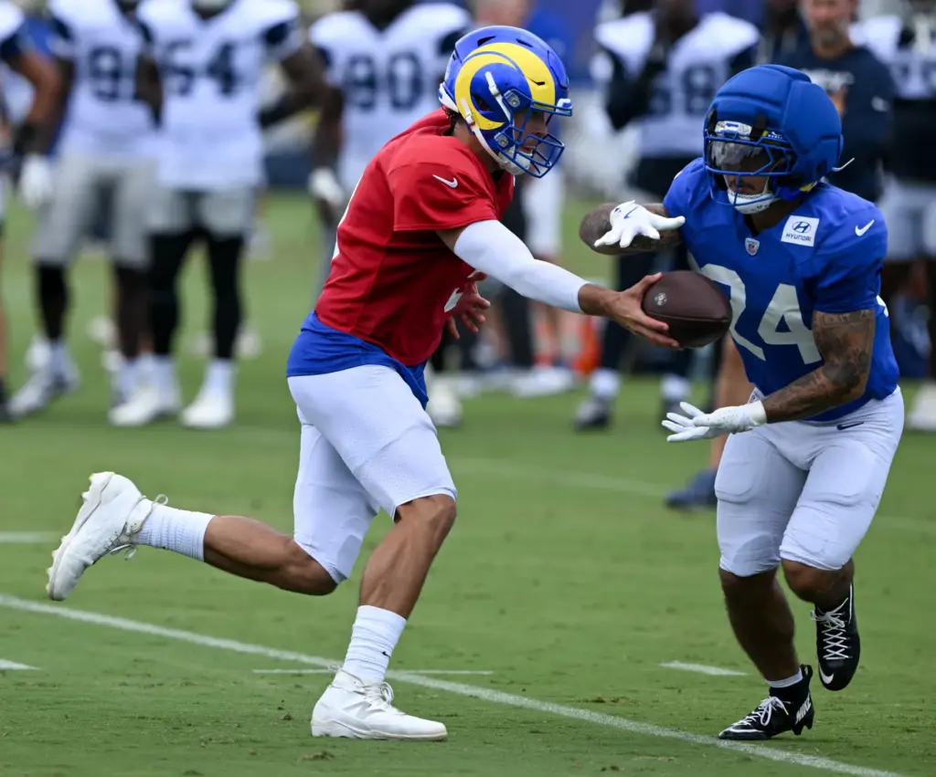 Rams starting quarterback Matthew Stafford, left, hands the ball off...