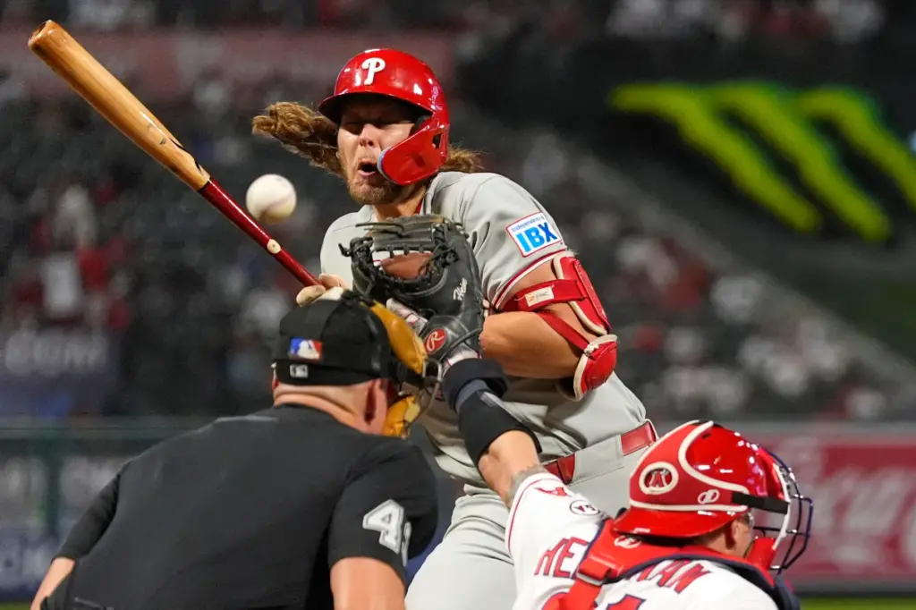 The Philadelphia Phillies’ Alec Bohm, center, is hit by a...