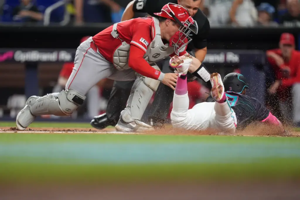 Angels catcher Tyler Heineman, left, tags out the Miami Marlins’...