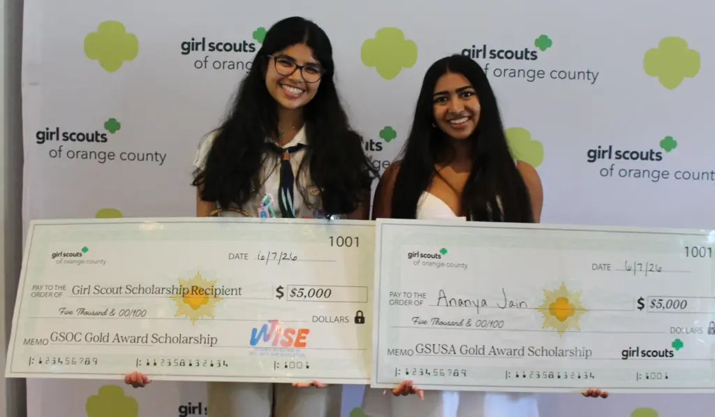 Aarna Mahale, left, and Ananya Jain each hold mock $5,000...