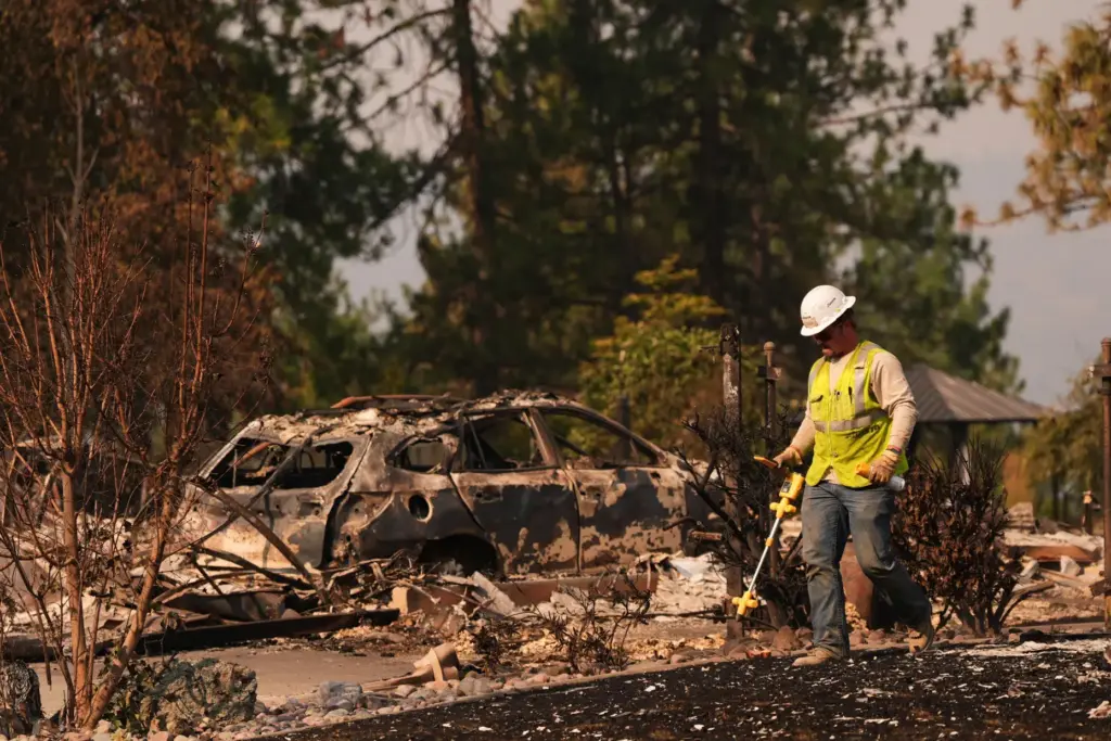 A worker with Avista moves through a property after a wildfire hit.