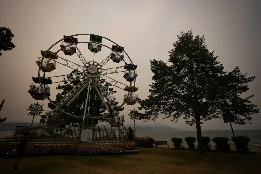 People ride a ferris wheel as smoke from the Bald...