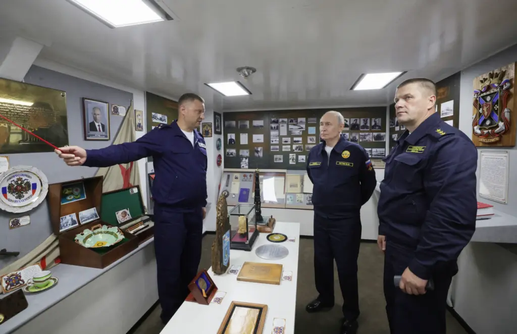 Russian President Vladimir Putin, center, listens to a navy officer...