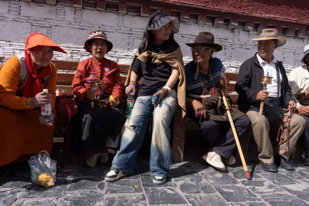 Qongqiu Quco, a 19-year-old student, sits with her relatives outside Jokhang Temple.