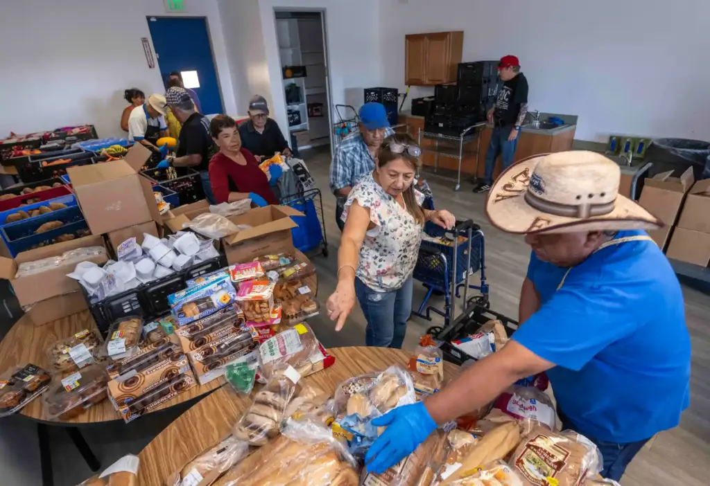 Volunteer Ricardo Castelaso, right, helps distribute food to community members...