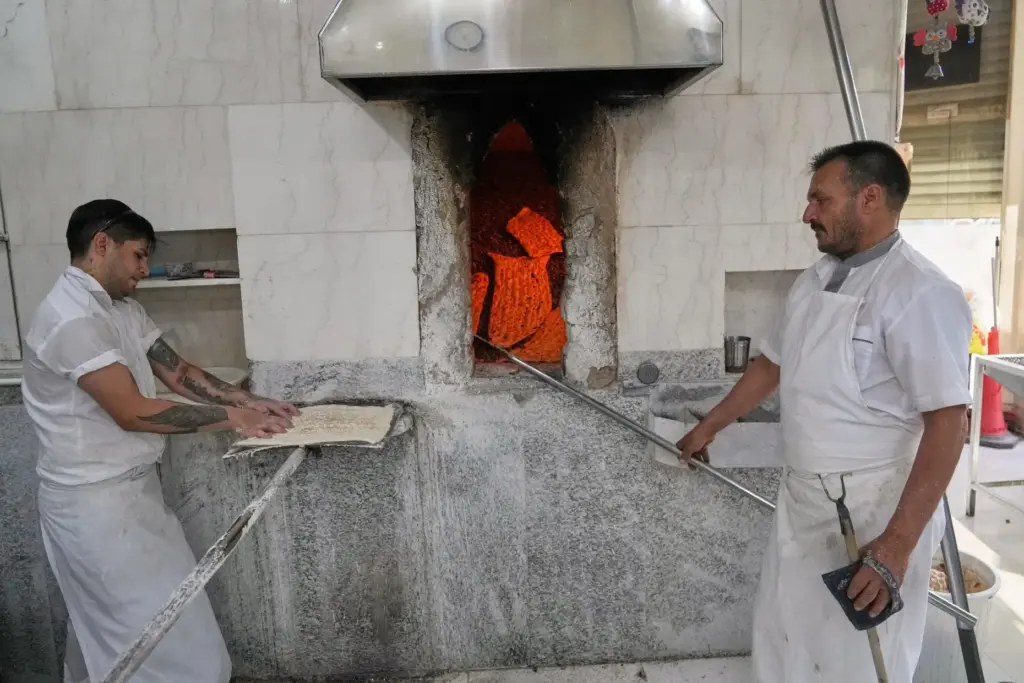Workers prepare sangak, a traditional Iranian flatbread, at a bakery...