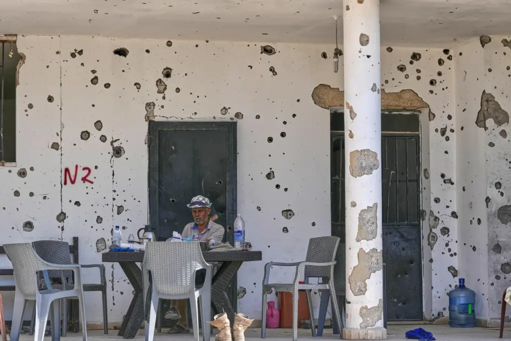 A Lebanese man sits outside his damaged house in the village of Zawtar al-Gharbieh.