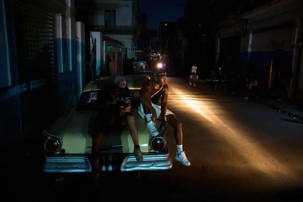 Men sit on the trunk of a car during a...