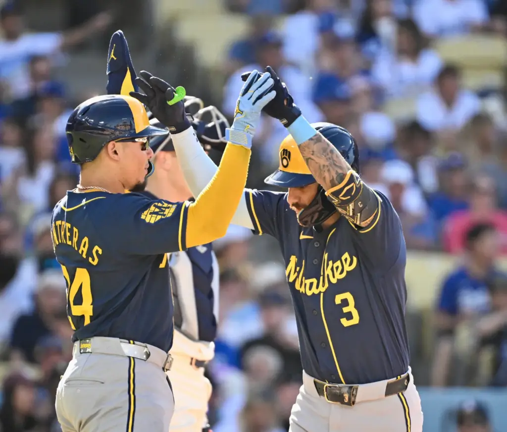 Joey Ortiz of the Milwaukee Brewers high fives teammate William...
