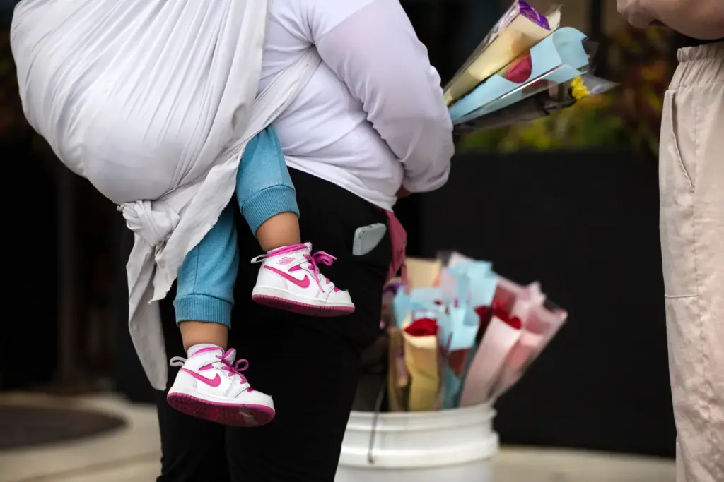 A woman carries her child while selling flowers on Randolph Street in Chicagoâs Fulton Market neighborhood.