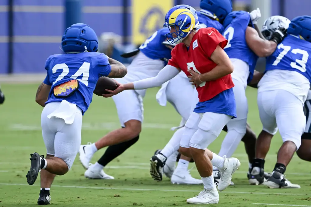 Rams quarterback Matthew Stafford, right, hands the ball off to...