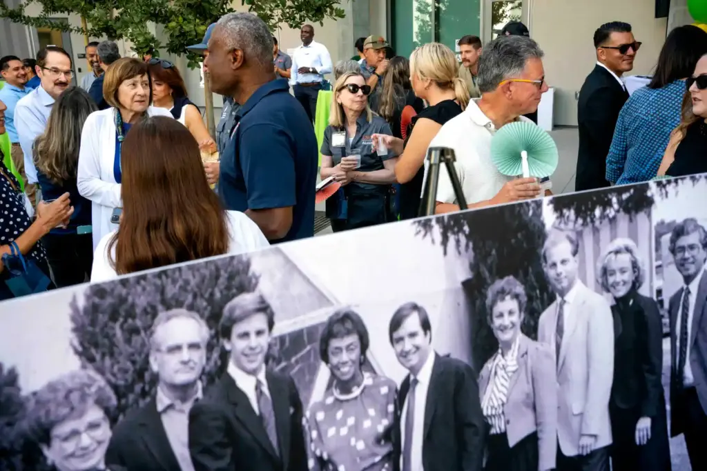 Attendees socialize behind a portrait from a 1986 groundbreaking ceremony...