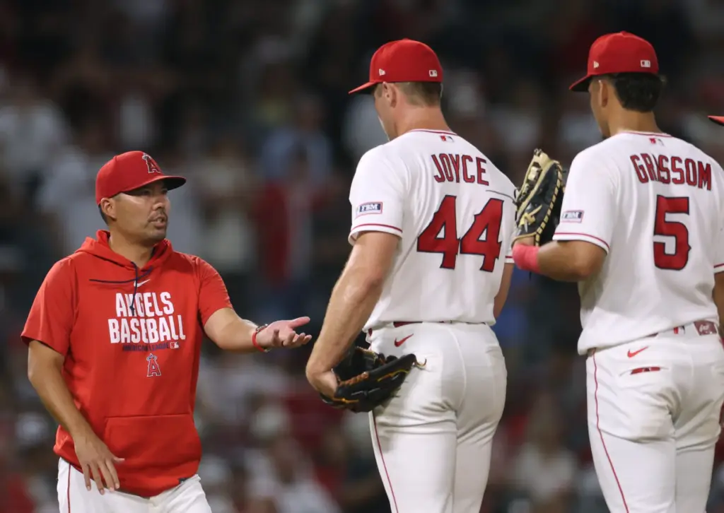 Angels manager Kurt Suzuki, left, takes the ball from relief...