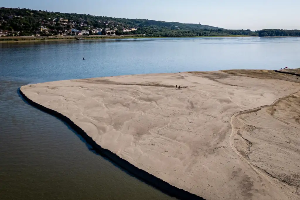 People walk on a bank of sand on the Danube...